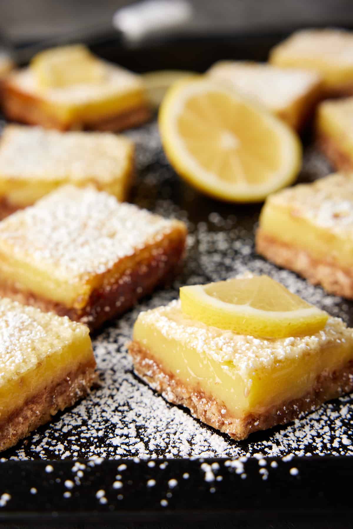 Coconut lemon bars on a dark sheet pan. 