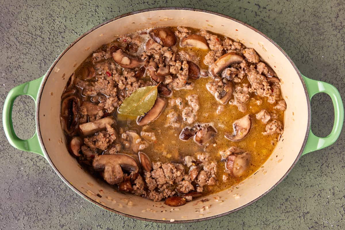 Dutch oven with browned sausage, mushrooms, shallots, white wine and bay leaf. 