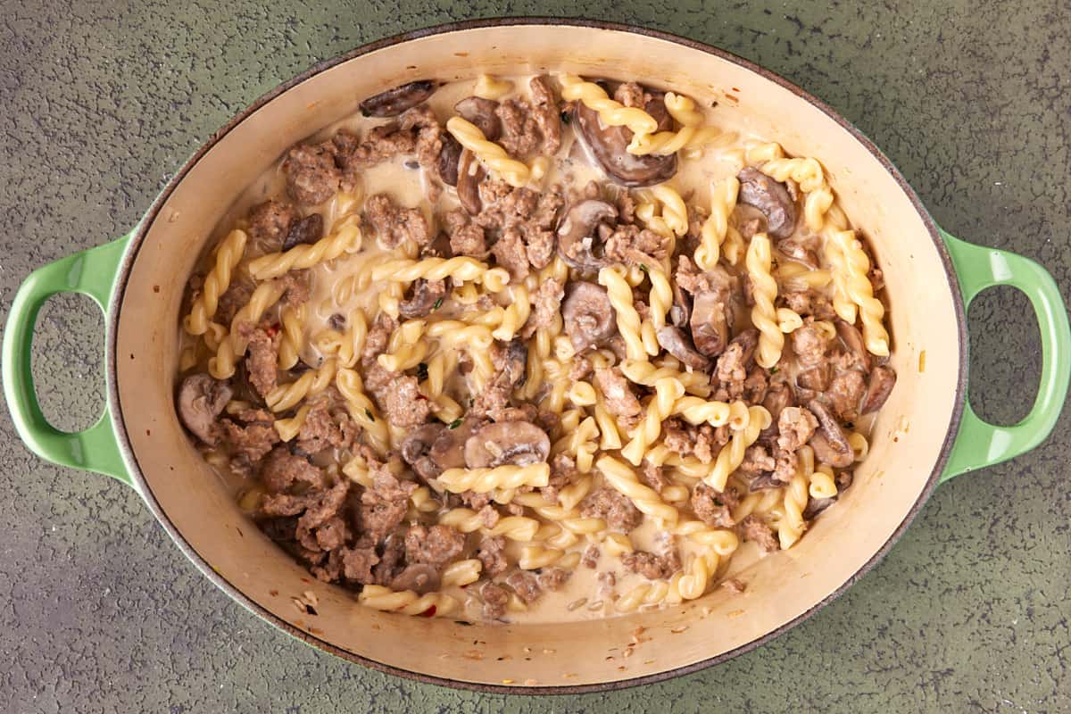 Dutch oven filled with creamy sausage gemelli pasta. 