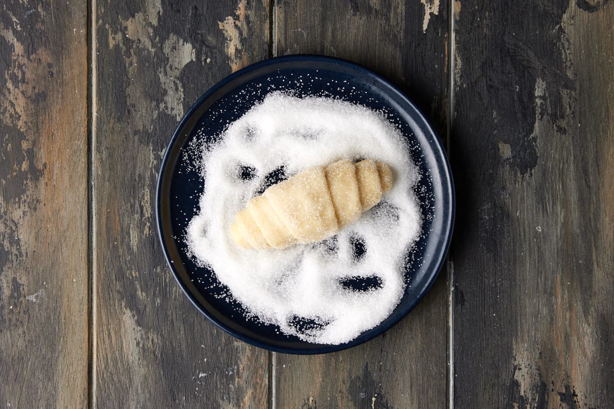 Croissant dough rolled in sugar on a dark plate. 