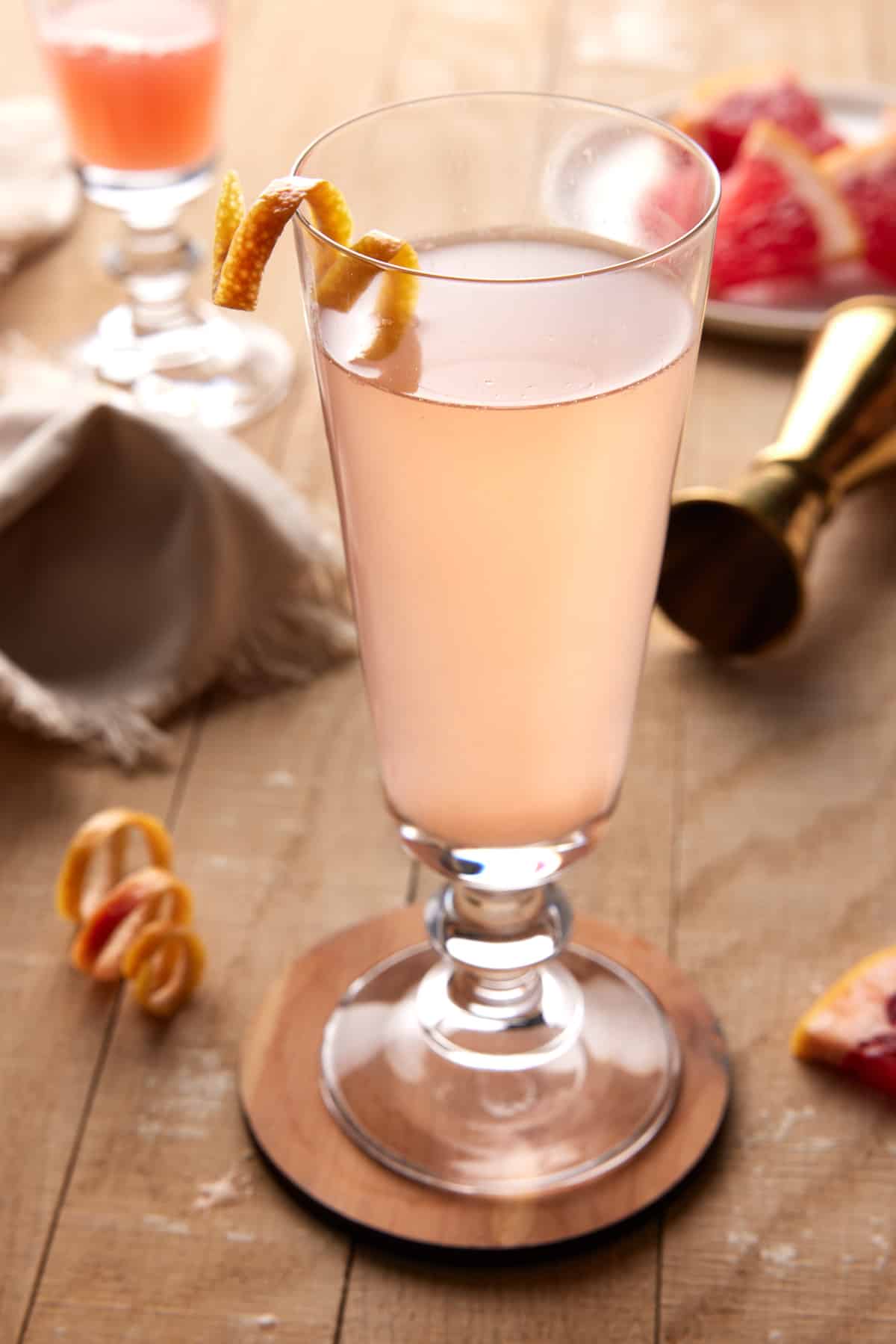 Grapefruit mimosa in a fluted glass on a light wood board. 
