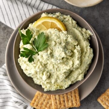 Lemon artichoke dip in gray bowl with crackers.