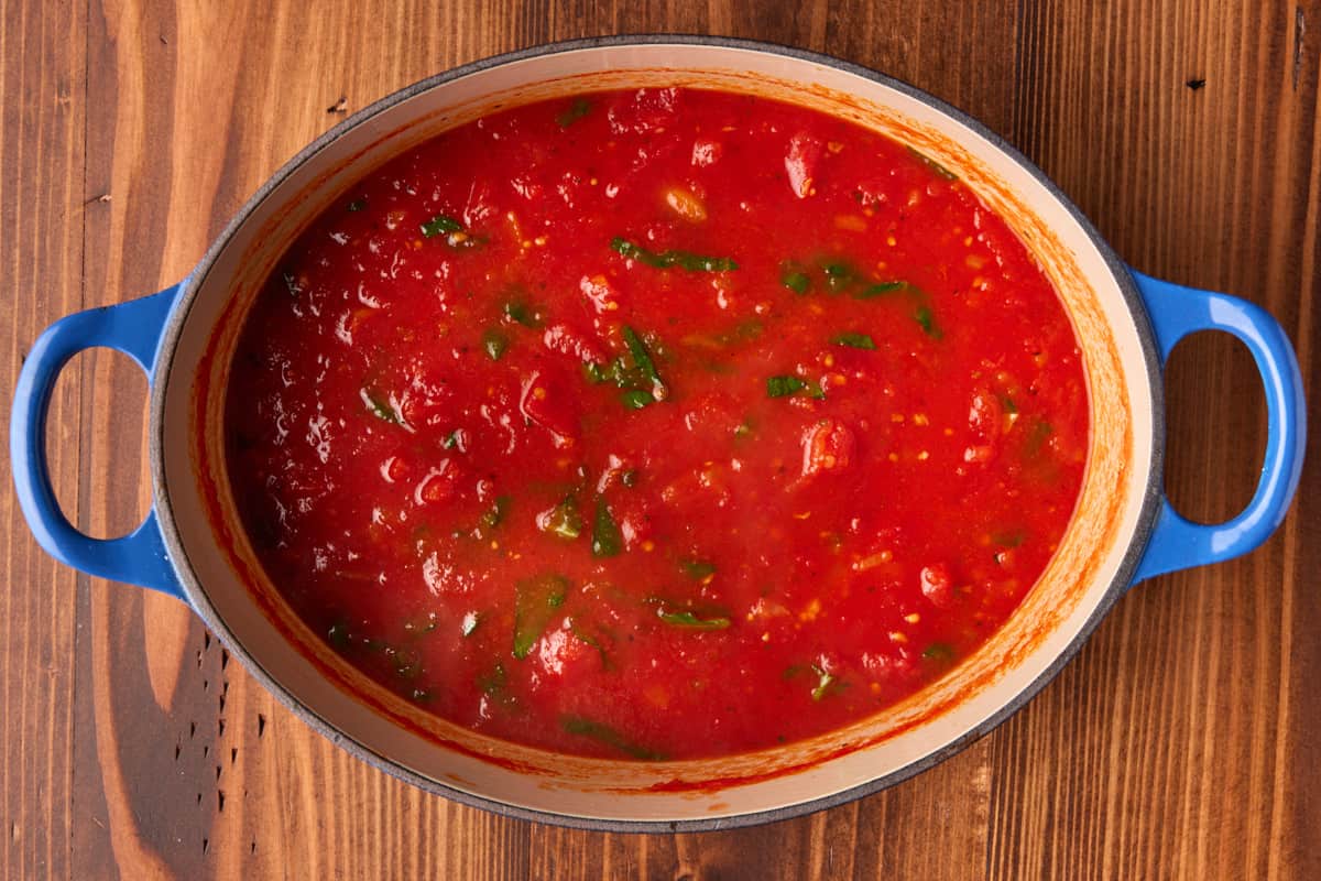 Tomato sauce in dutch oven with fresh basil.