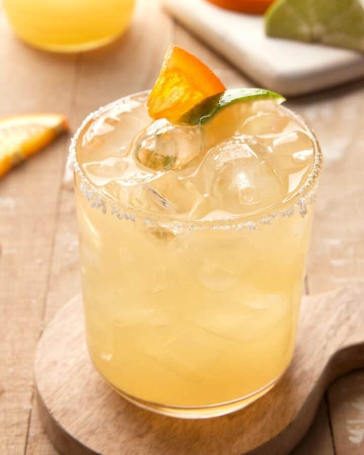 Margarita on ice with orange wedge.