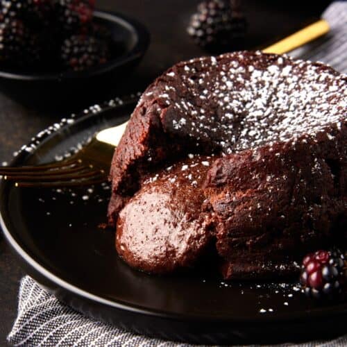 Molten chocolate lava cake with oozing center on dark plate.