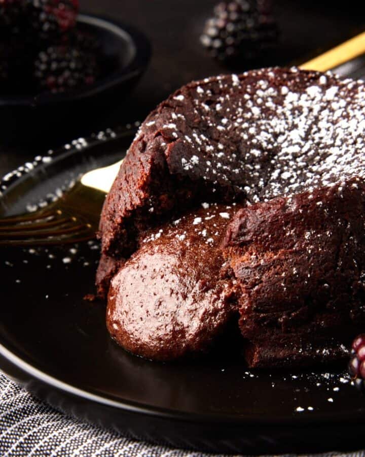 Molten chocolate lava cake with oozing center on dark plate.