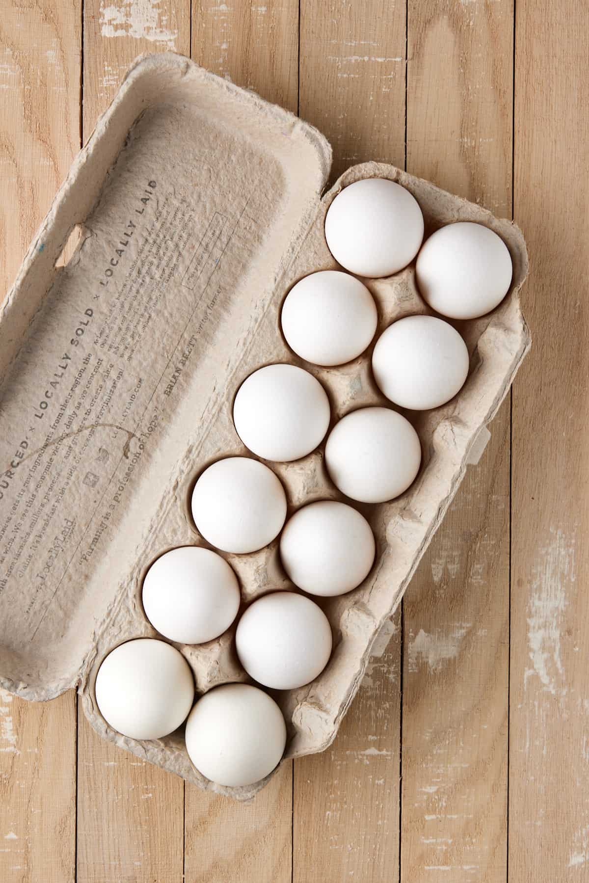 Dozen white eggs in carton.