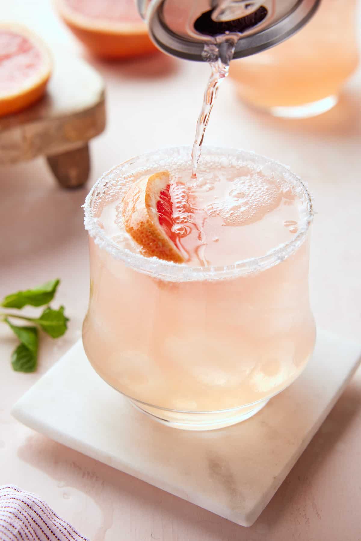 Pouring grapefruit soda into slated rim glass.