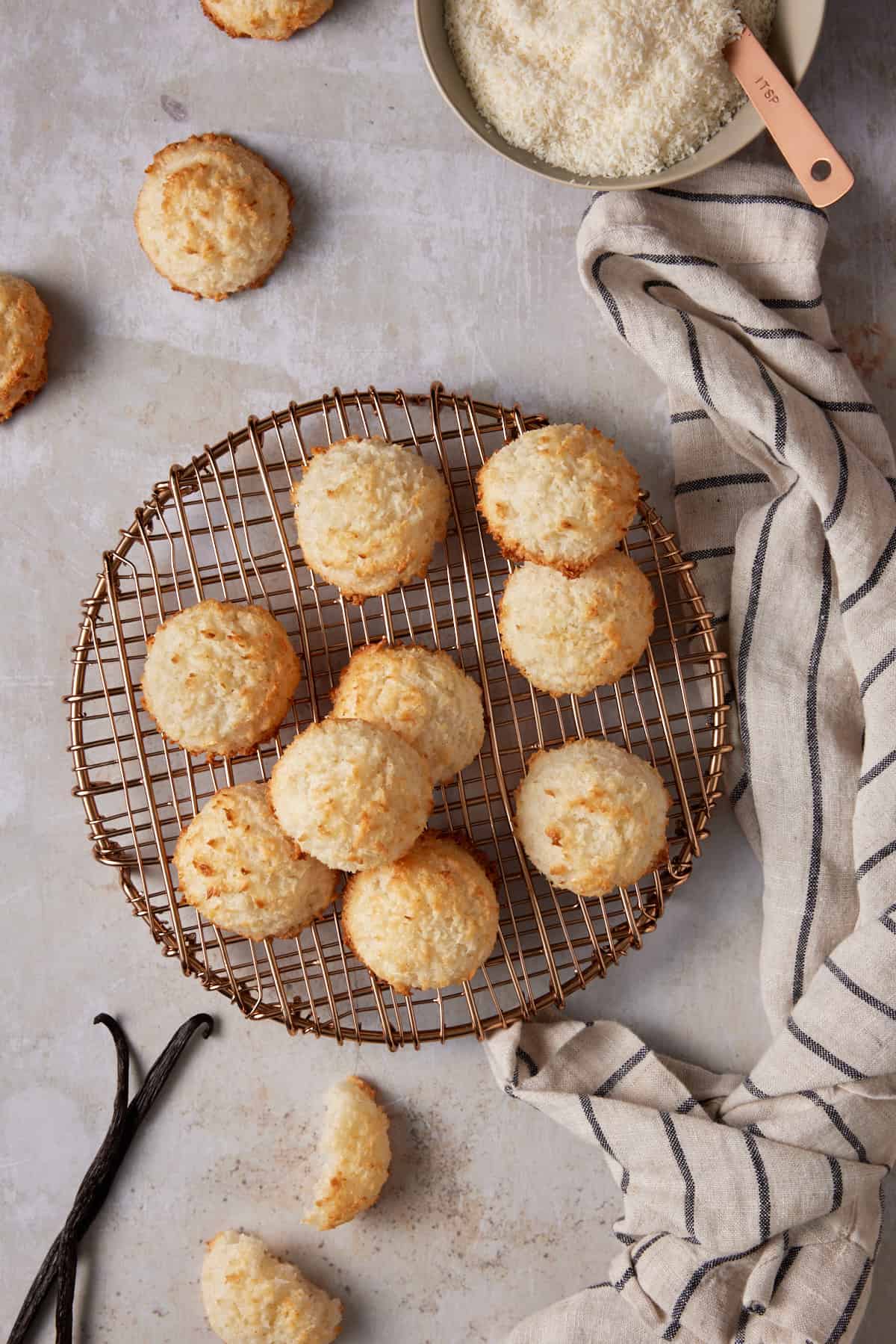 Coconut macaroons on a copper cooling rack with a striped kitchen towel.