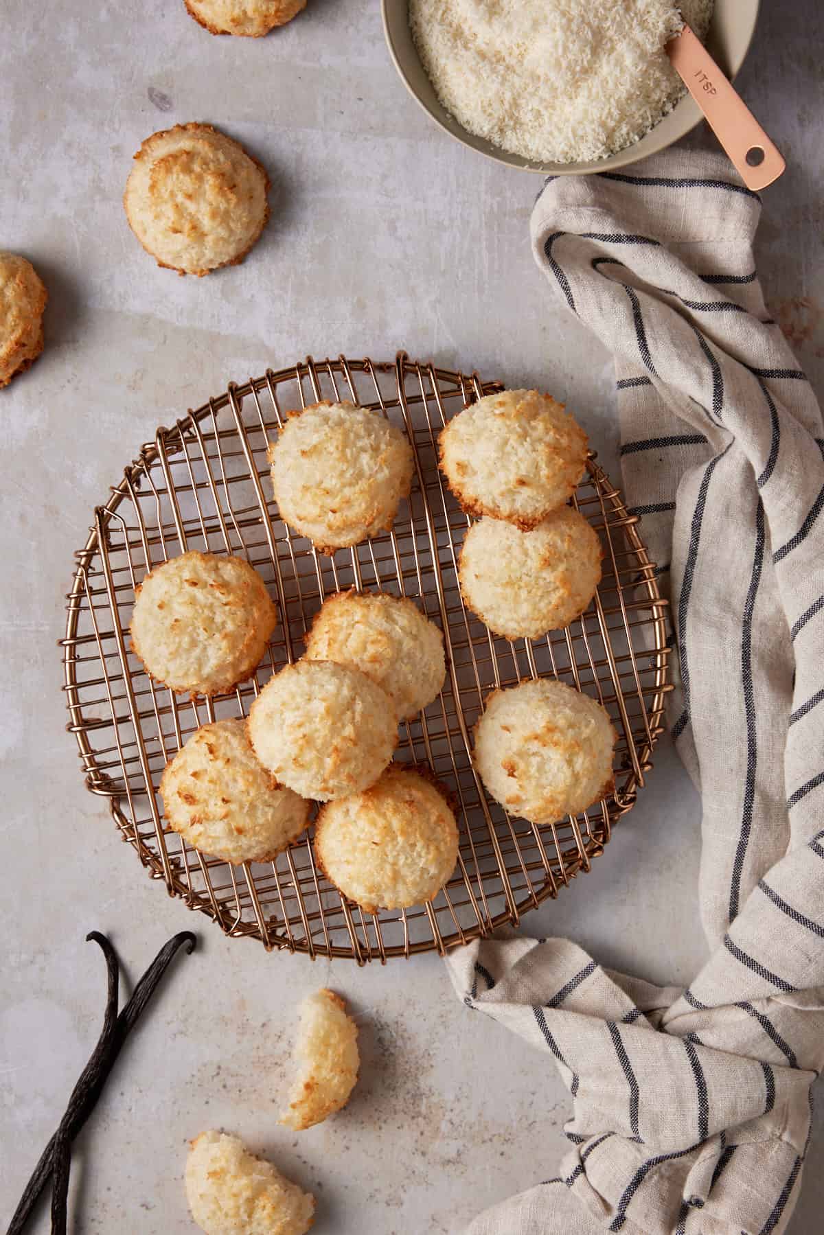 Coconut macaroons on a copper cooling rack with a striped kitchen towel. 