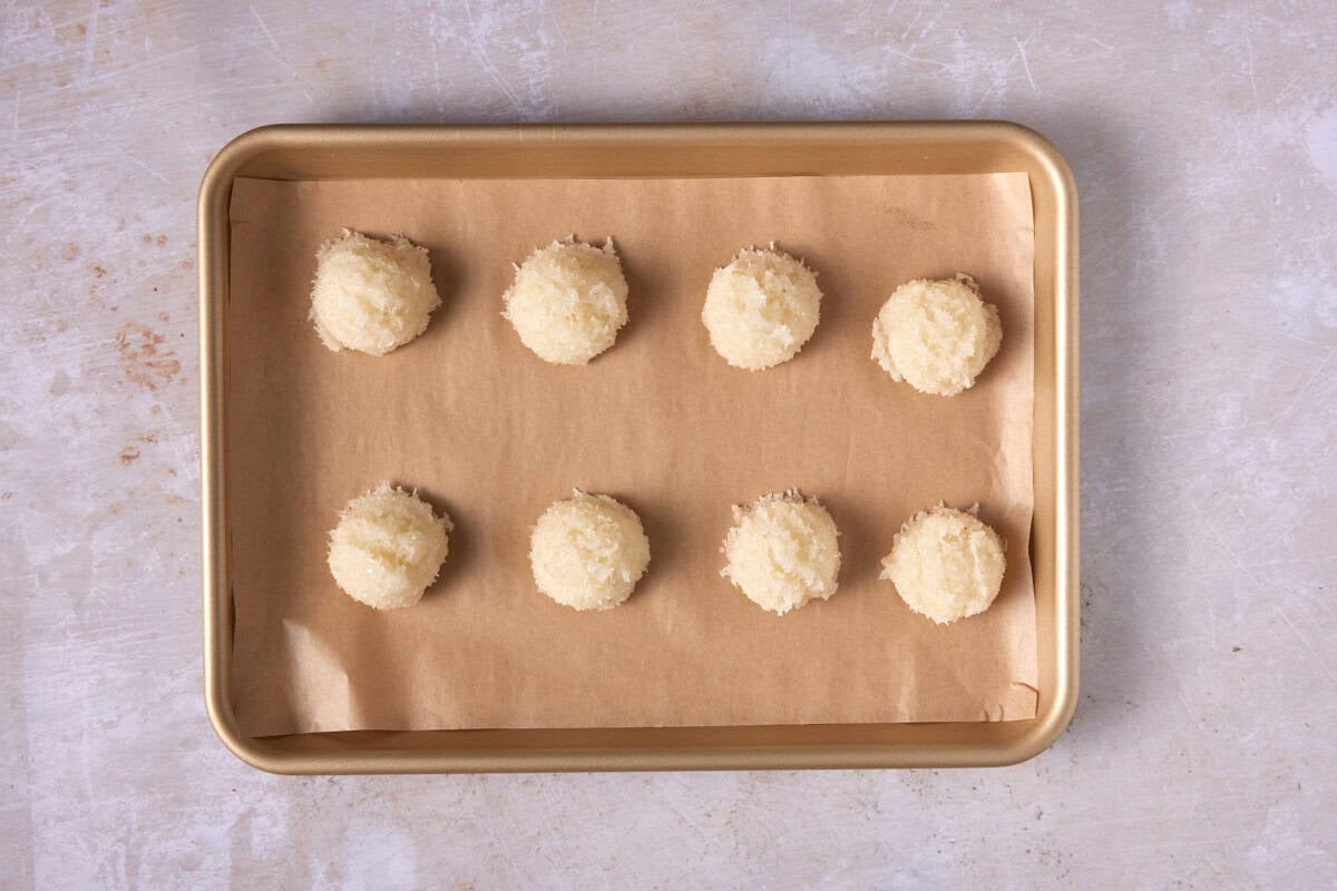 Unbaked coconut macaroons on a cookie sheet.