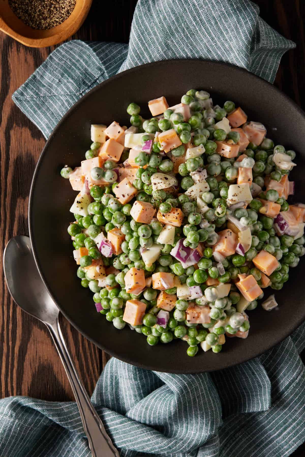 Pea salad with cheese and red onion on plate.