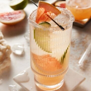 Grapefruit paloma in highball glass garnished with grapefruit and lime slices.