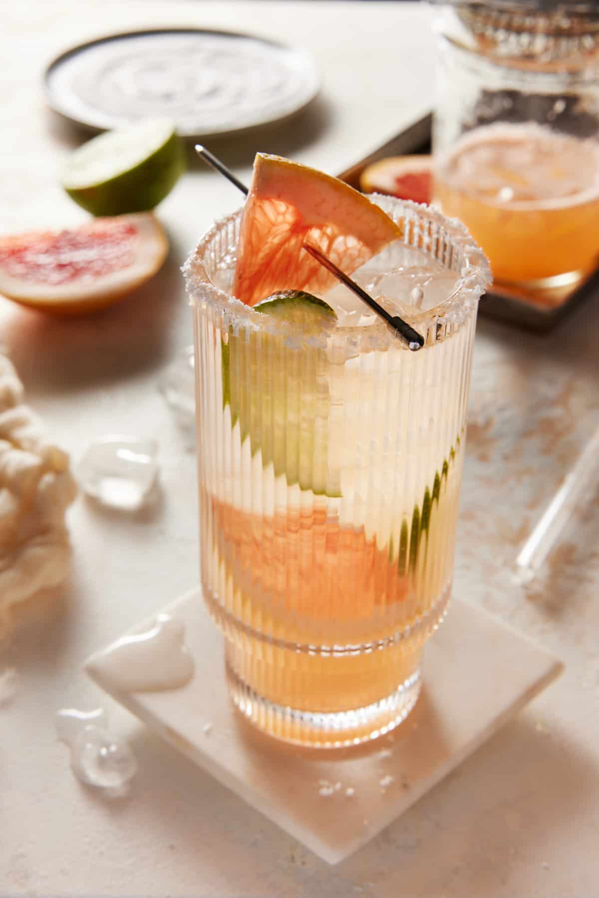 Highball glass filled with ice, grapefruit wedges and paloma cocktail. 
