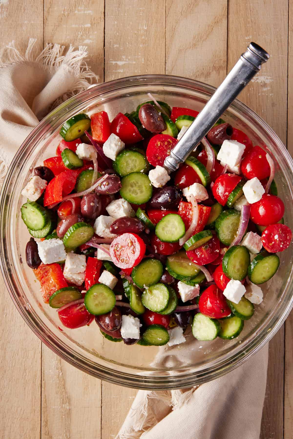 Greek Cucumber Salad in a glass bowl with a spoon and beige linen. 