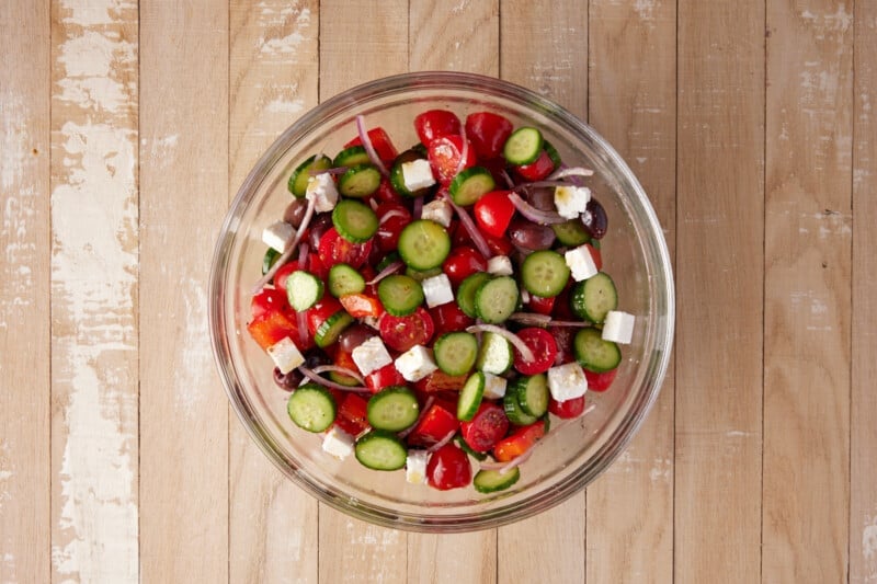 Greek Cucumber salad in a glass bowl with a spoon.