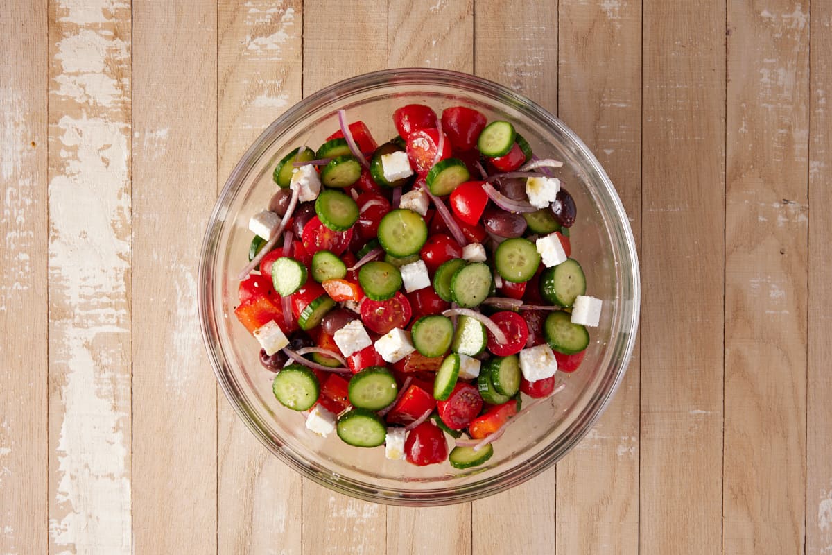 Greek Cucumber salad in a glass bowl with a spoon. 