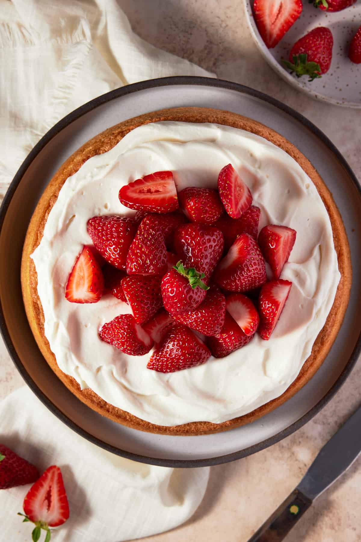 Whole Almond Flour Cake garnished with whipped cream and strawberries on a plate. 