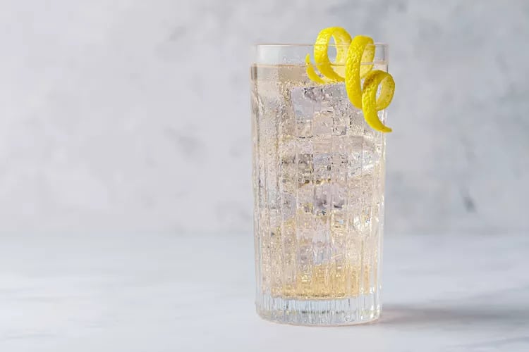 Cocktail in ribbed highball glass with lemon peel from The Spruce Eats.