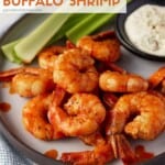 Buffalo Shrimp recipe with celery sticks on a plate with blue cheese for dipping.
