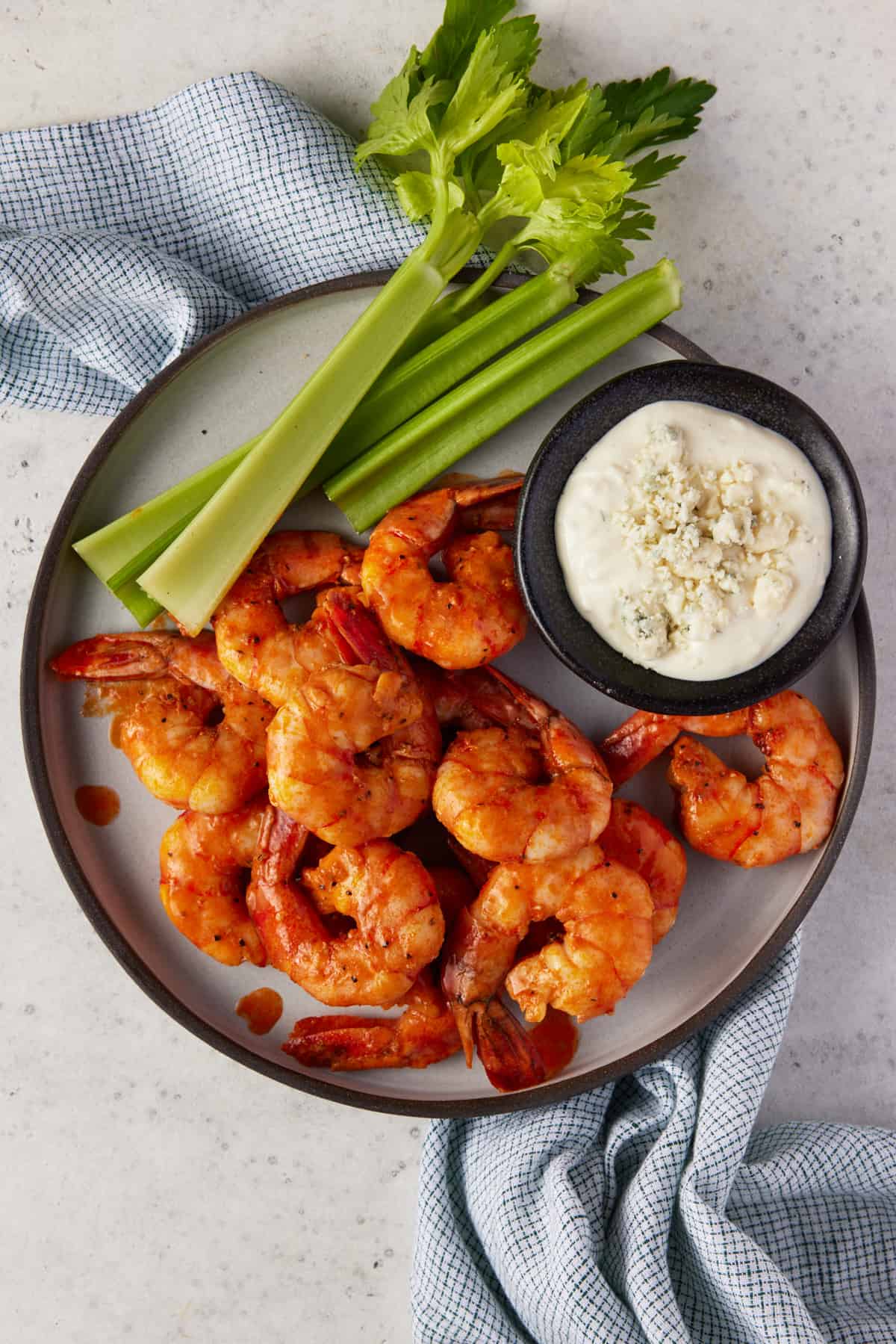 Buffalo shrimp on a plate wiht blue cheese and celery.