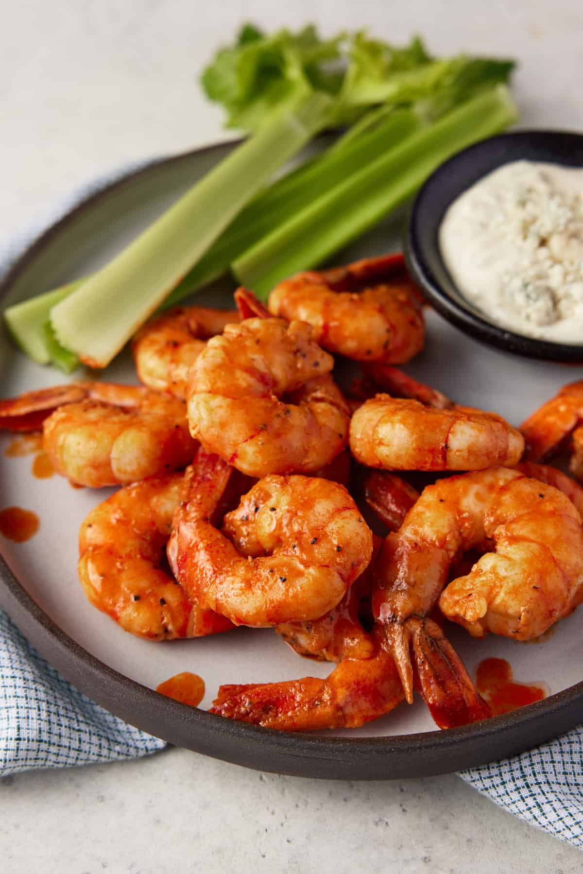 Spicy shrimp on a plate with celery sticks.
