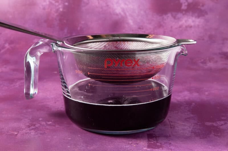 Measuring cup with strainer to catch blueberries.