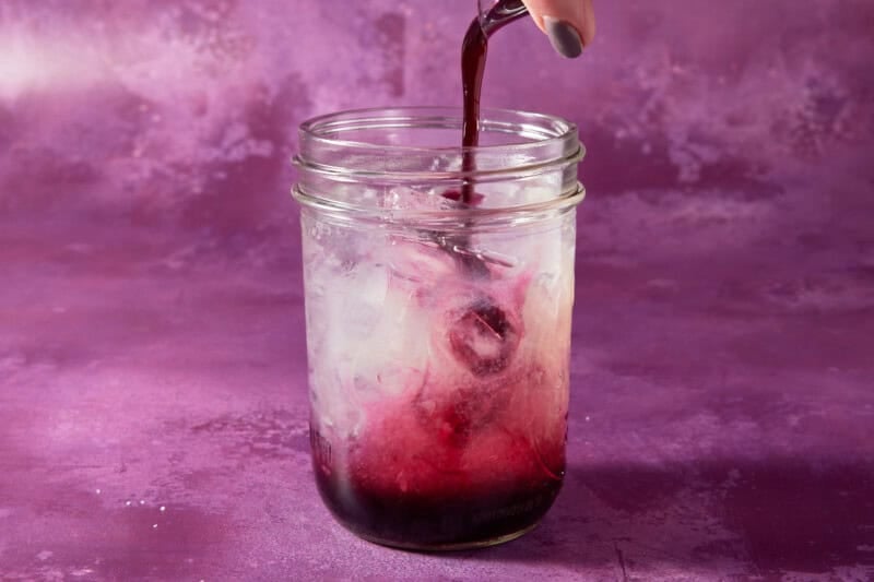 Shaker with blueberry syrup being added.