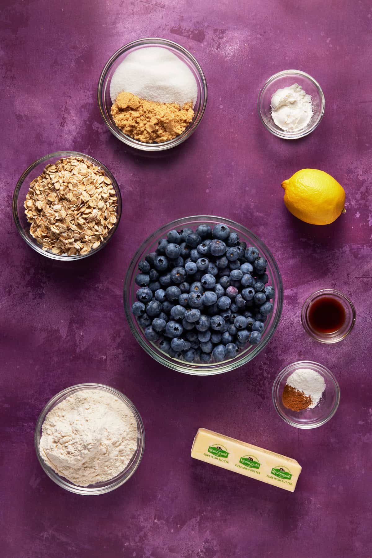 Bowls of ingredients for blueberry oat crumble bars, including blueberries, flour, oats and butter. 