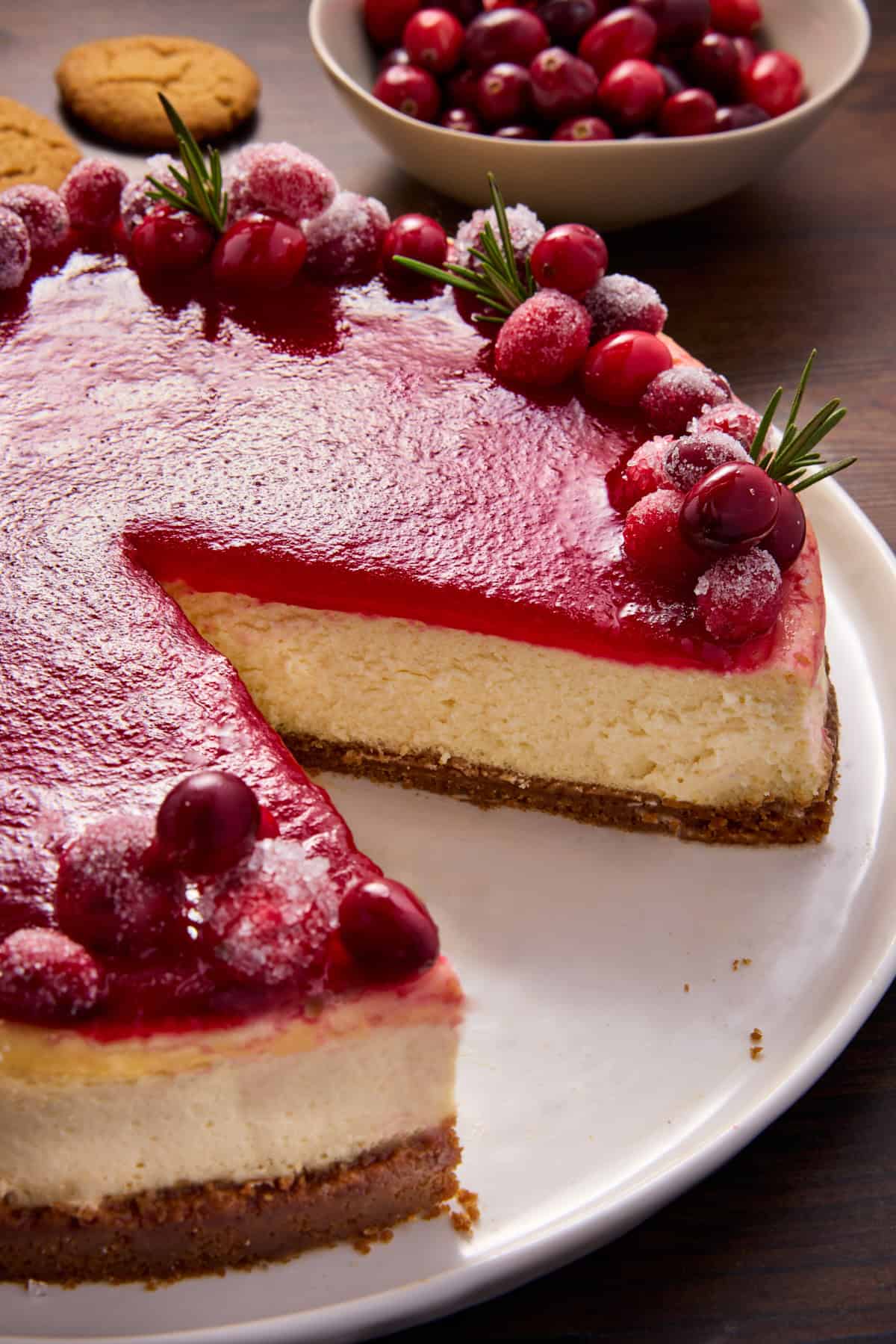 Side angle view of cheesecake topped with cranberry glaze and sugared cranberries. 