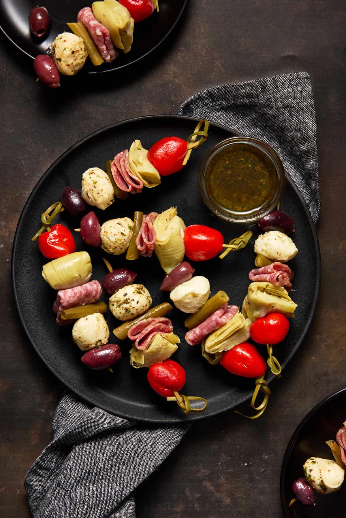Antipasto Skewers on plates with dipping sauce.