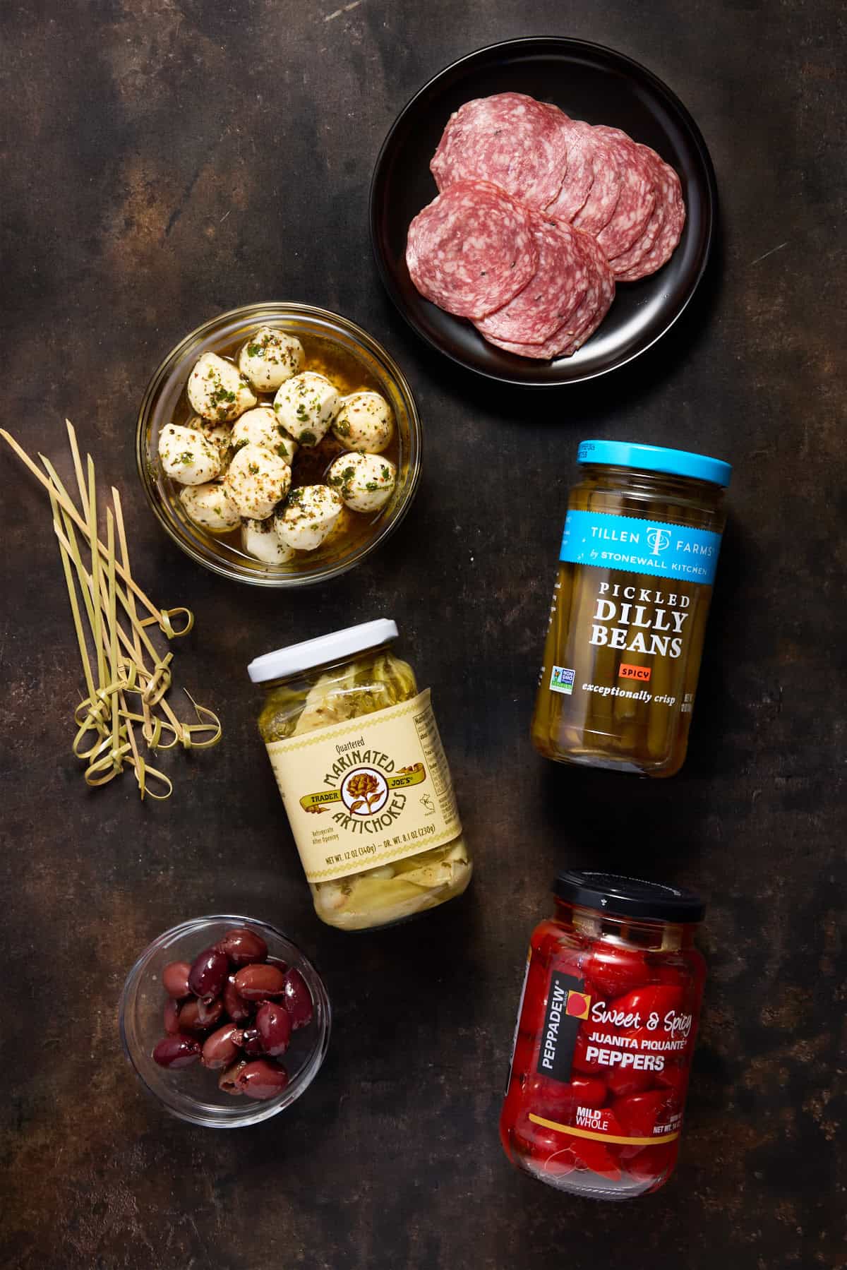 Jars of ingredients needed for anitpasto skewers.