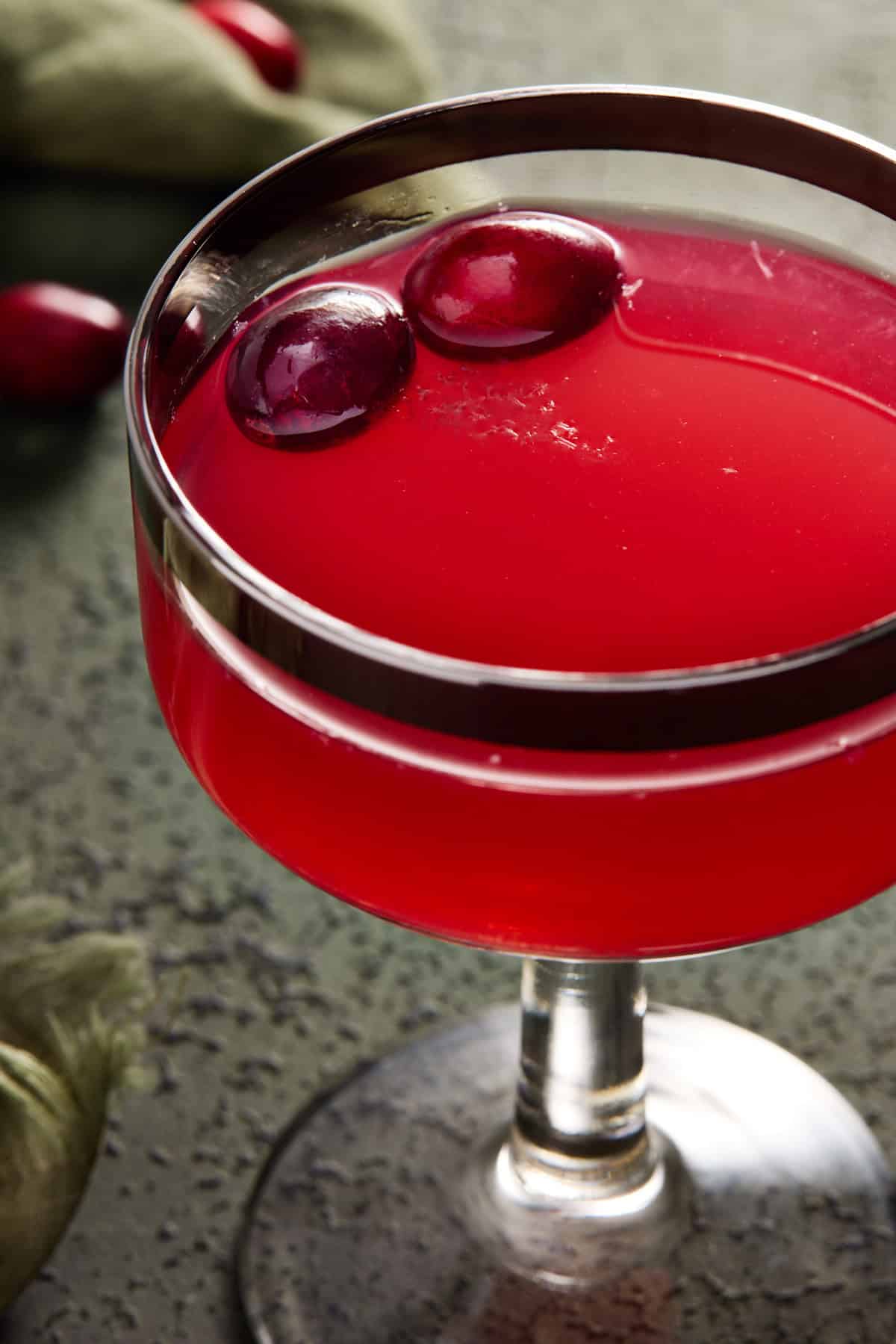 Cranberry drink in a coupe glass with fresh cranberries.