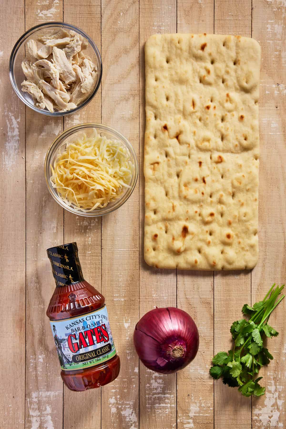 Ingredients for BBQ chicken flatbread on a wood board. 