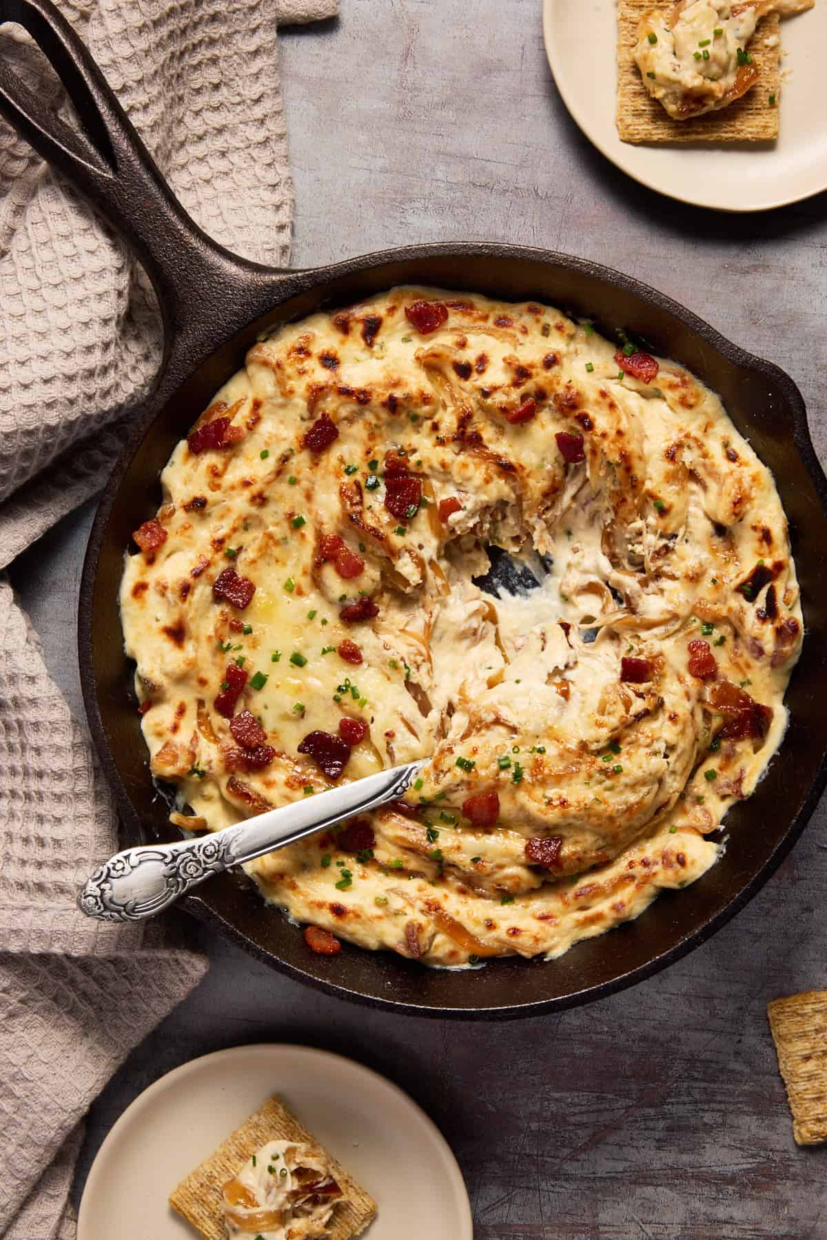 Onion dip with a spoon ready to eat in cast iron pan.