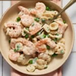 Shrimp and Pea pasta in bowl with fork and pink napkin.