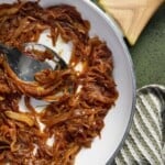 Caramelized onions in a pan with a green towel.