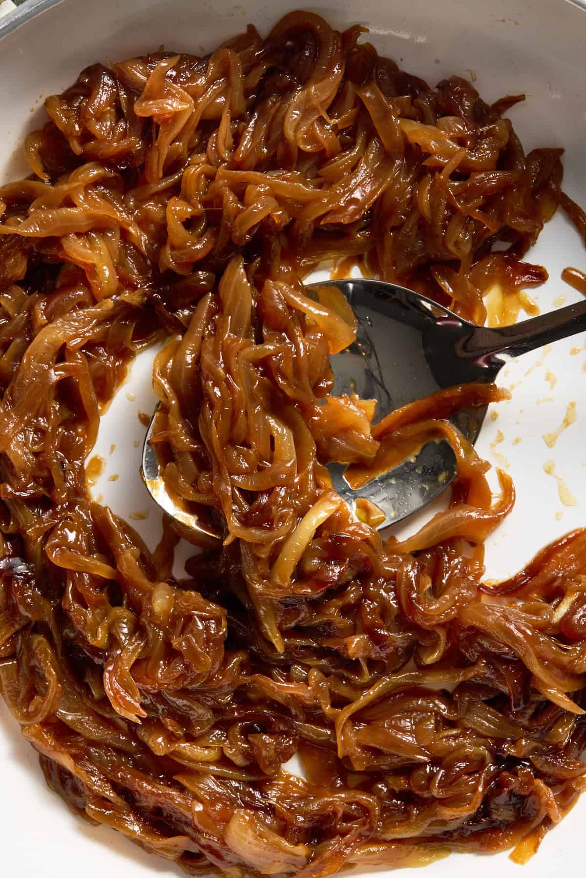 Caramelized onions on a spoon in a pan.