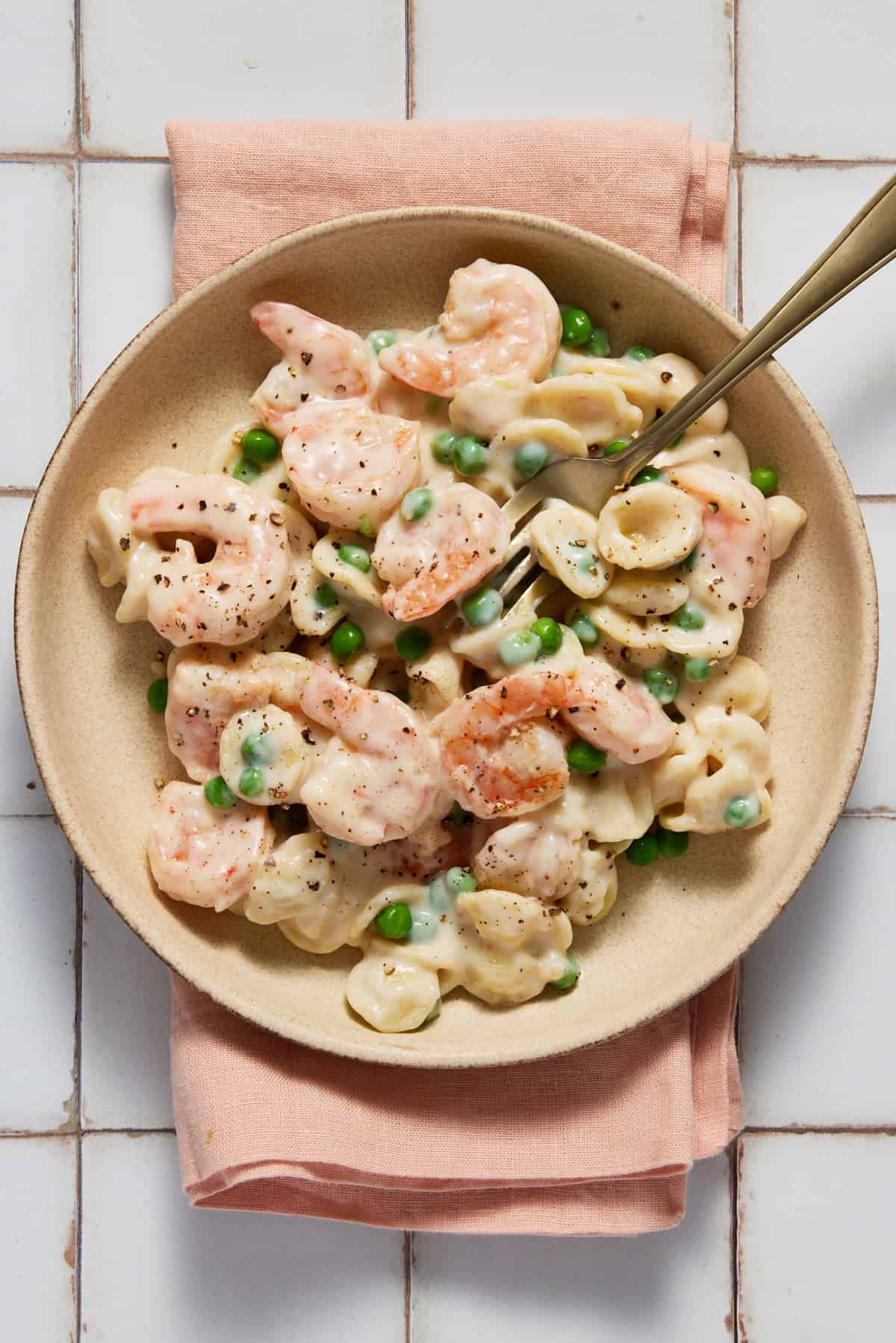 Shrimp and Pea Pasta on a plate with a napkin and fork.