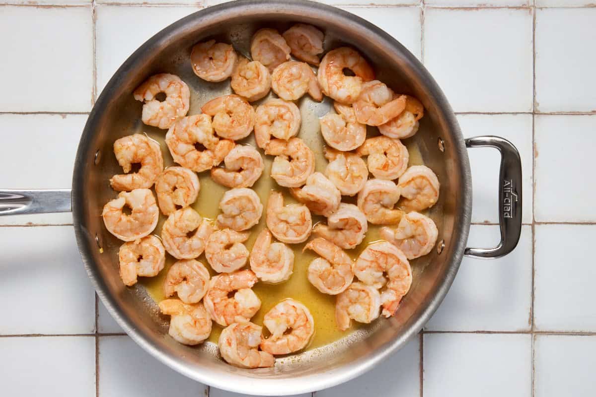 Cooked shrimp and white wine in pan.