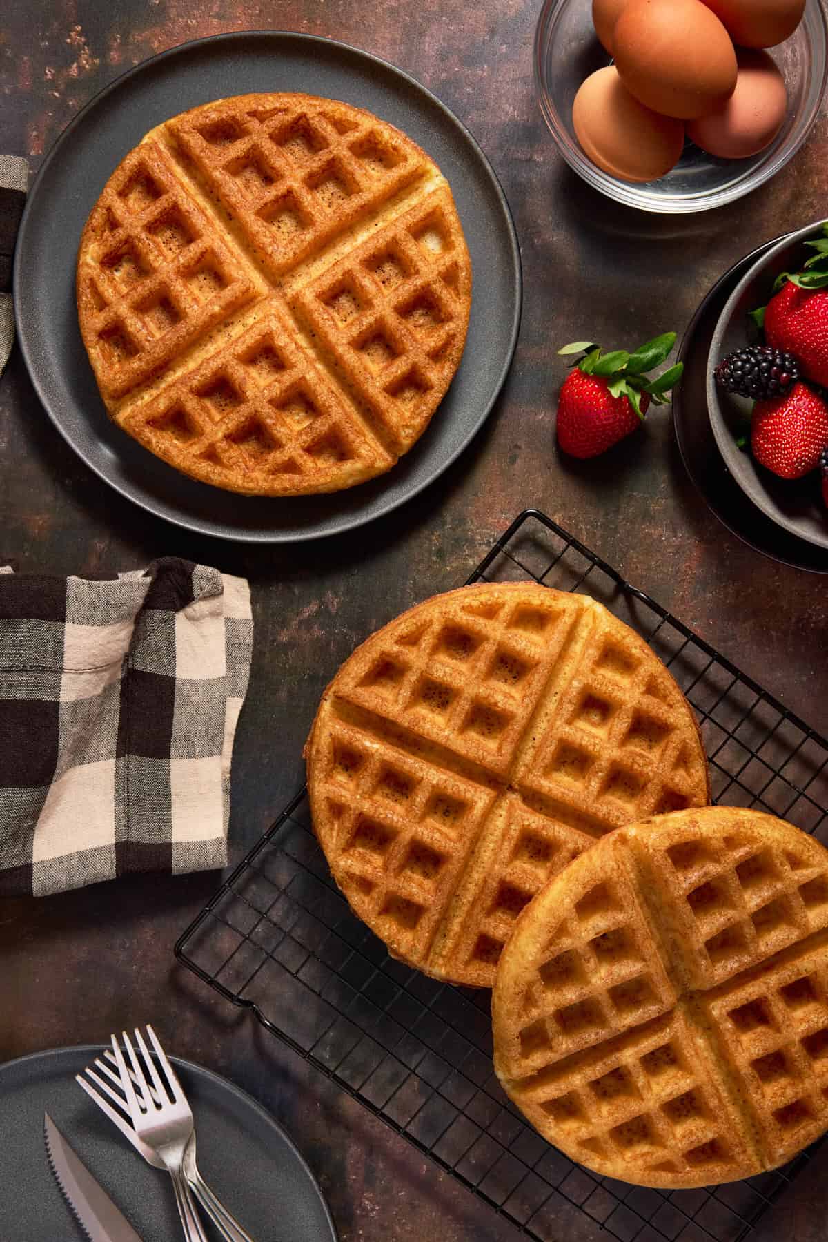 Overnight yeast waffles on a wire cooling rack and a dark plate. 