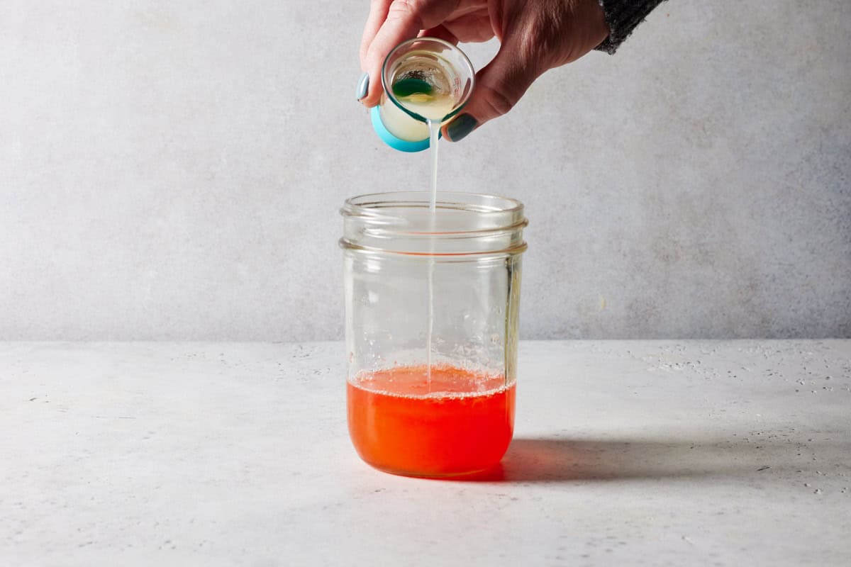 Egg white being poured into shaker for aperol sour.