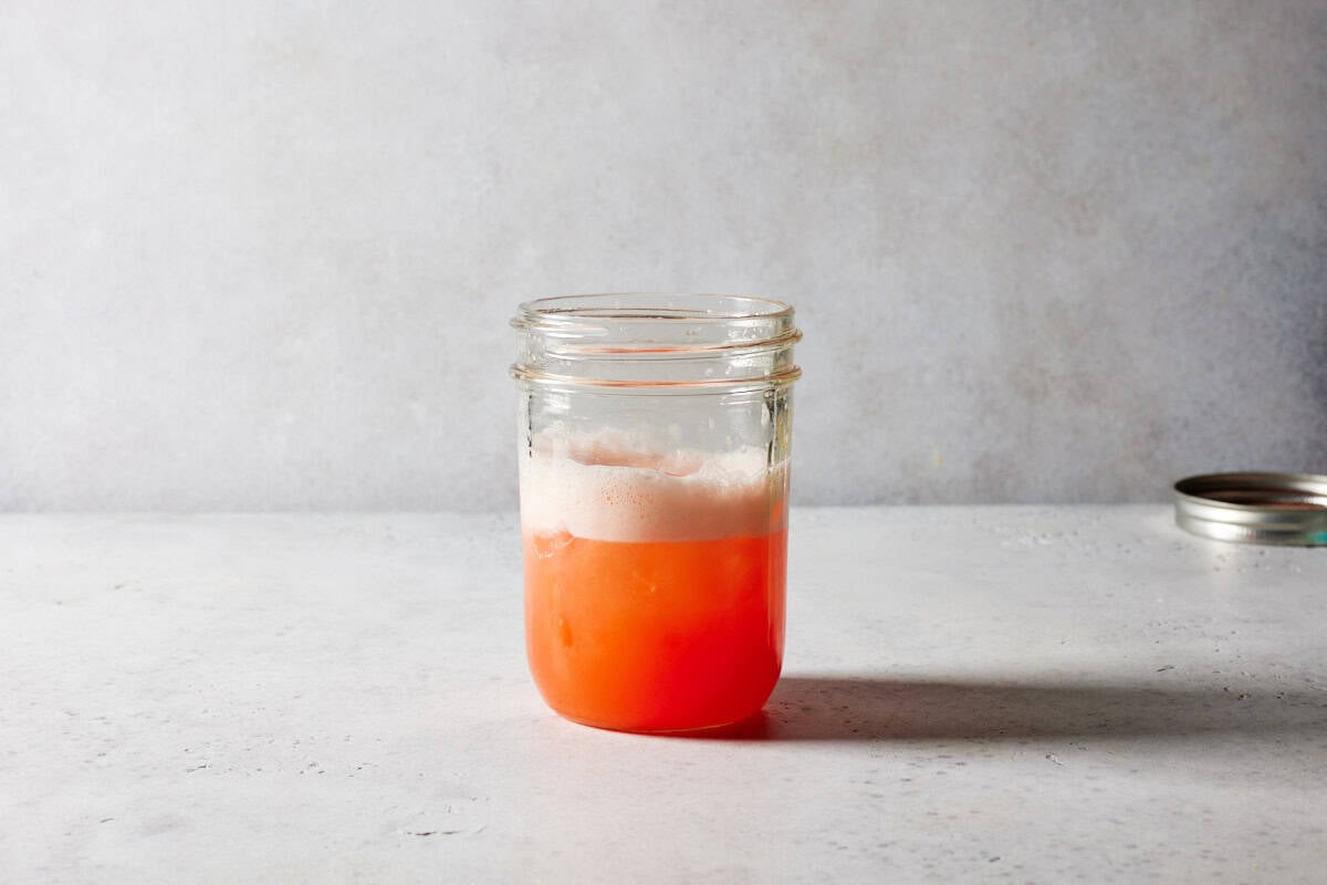 Aperol sour in shaker with ice.