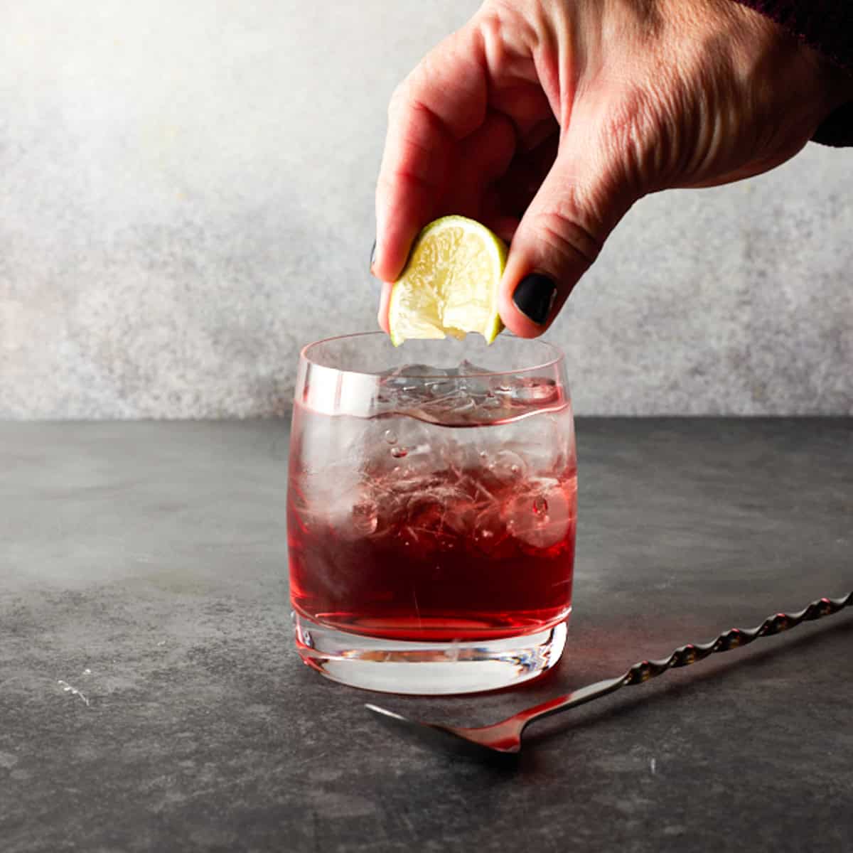 Lime wedge being squeezed in glass.