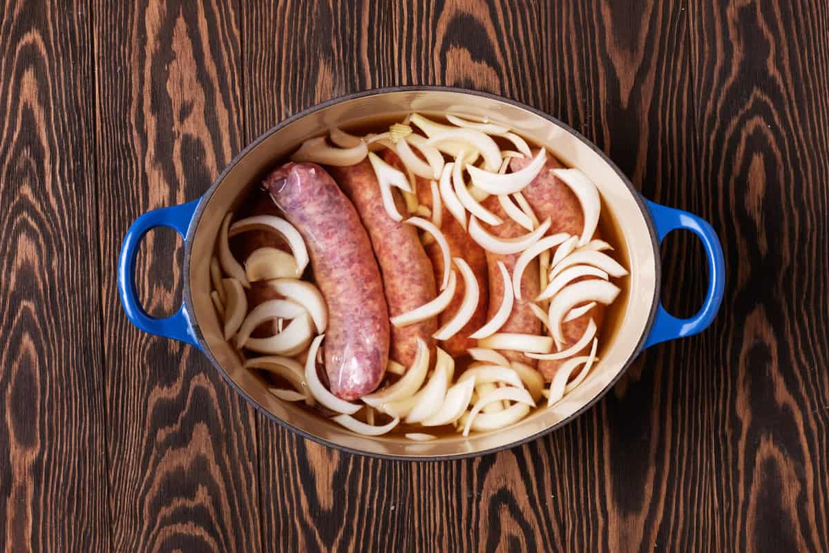 Raw brats and onions in beer in dutch oven.
