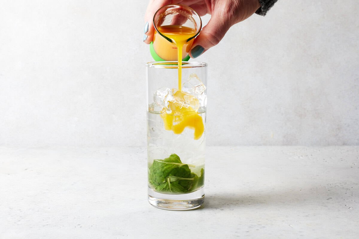 Mango juice being poured in glass.