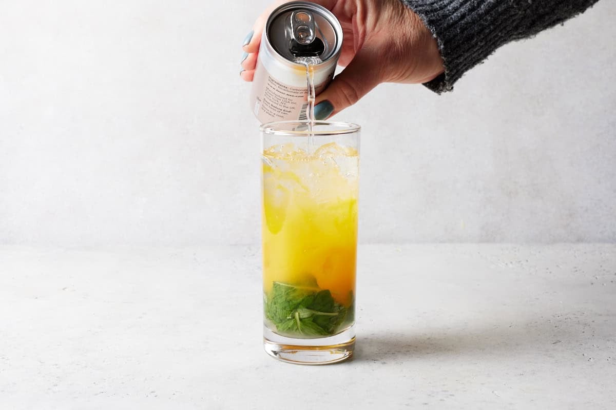 Club soda being poured in mango mojito.
