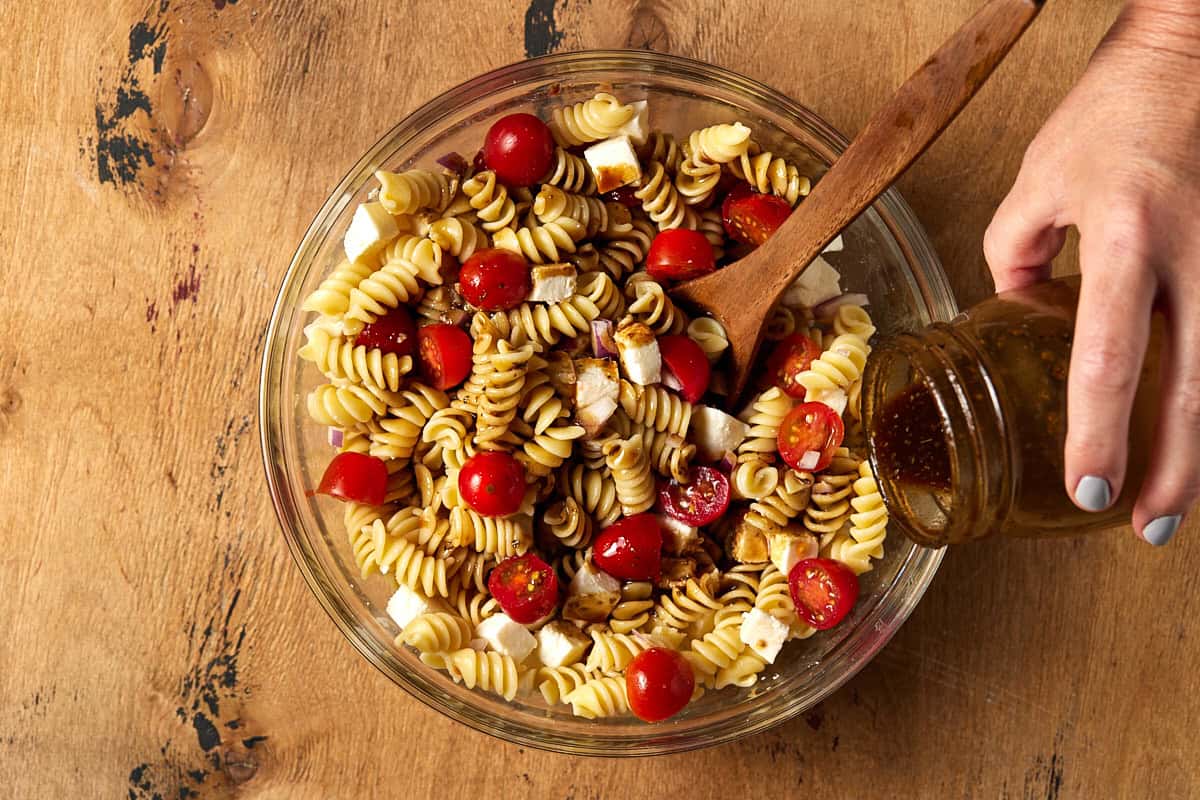 Balsamic dressing being poured over pasta.