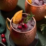 Cranberry Mules in copper mugs with fresh roasemary and orange slices.
