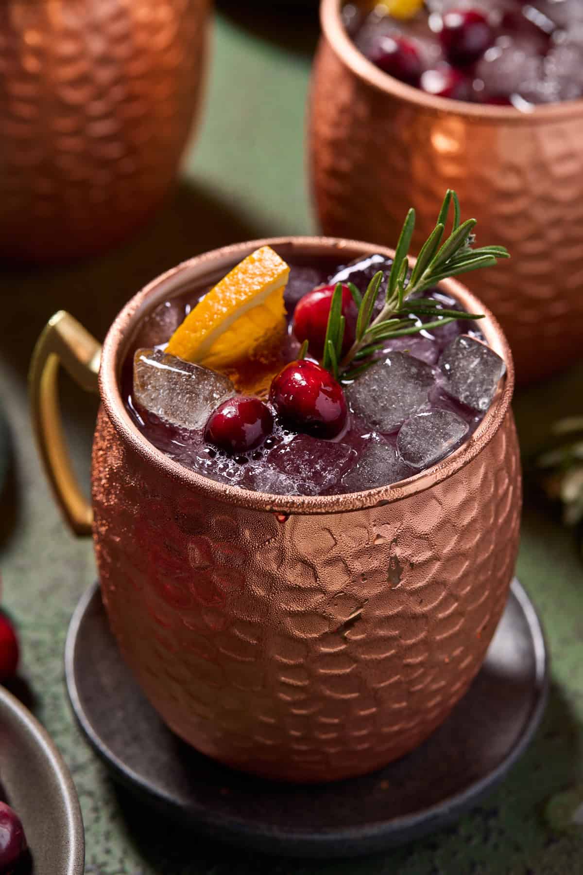 Cranberry mule in copper mug on a coaster.